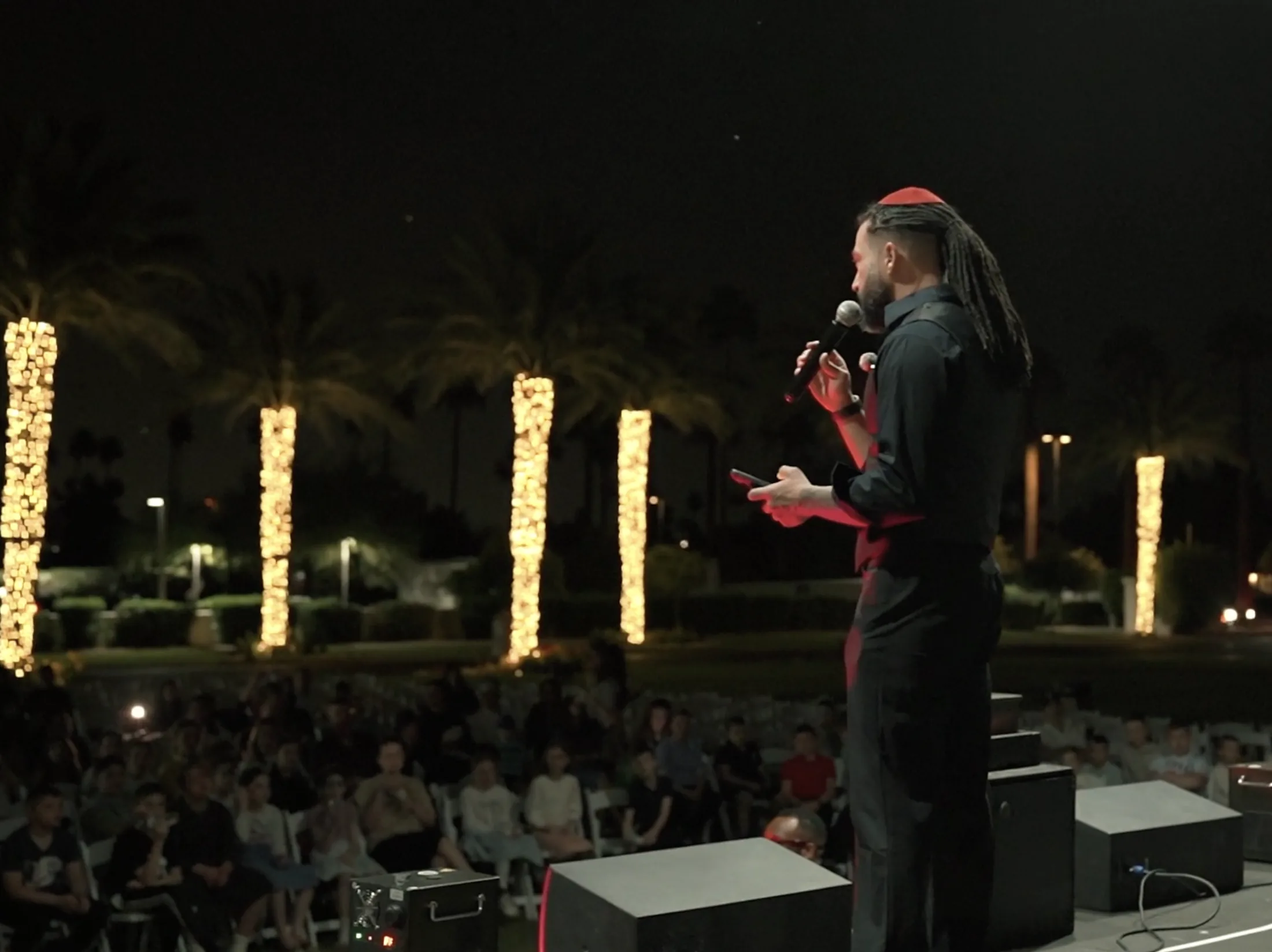 Joseph Cancilla speaking into a microphone at the Wigwam Passover event